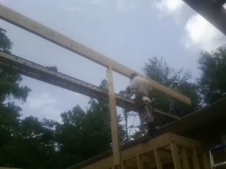 Carpenter setting a ridge beam over a new addition frame — Ice Dam Removal by Roofing Brothers in Martell