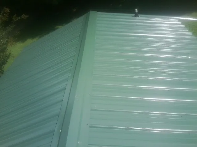 New green metal panels meeting at the ridge of a roof — Flat Roof Repair work by our crew in Martell