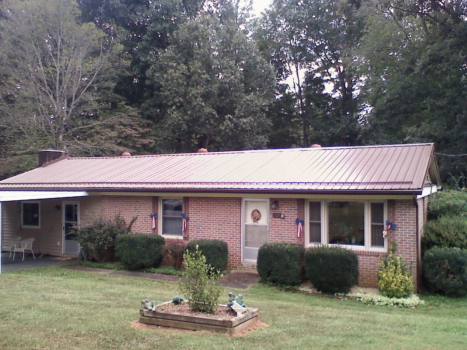 Bronze metal roof on a brick ranch home with a carport in Martell