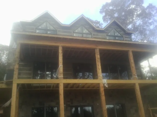 Dormers and porch framing on a large log home under construction — Roof Coating work by our crew in Martell