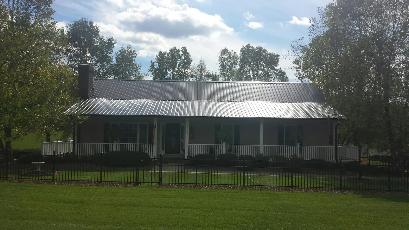 Gray metal roof on a brick ranch with a full width front porch — Gutter Guard Installation work by our crew in Martell