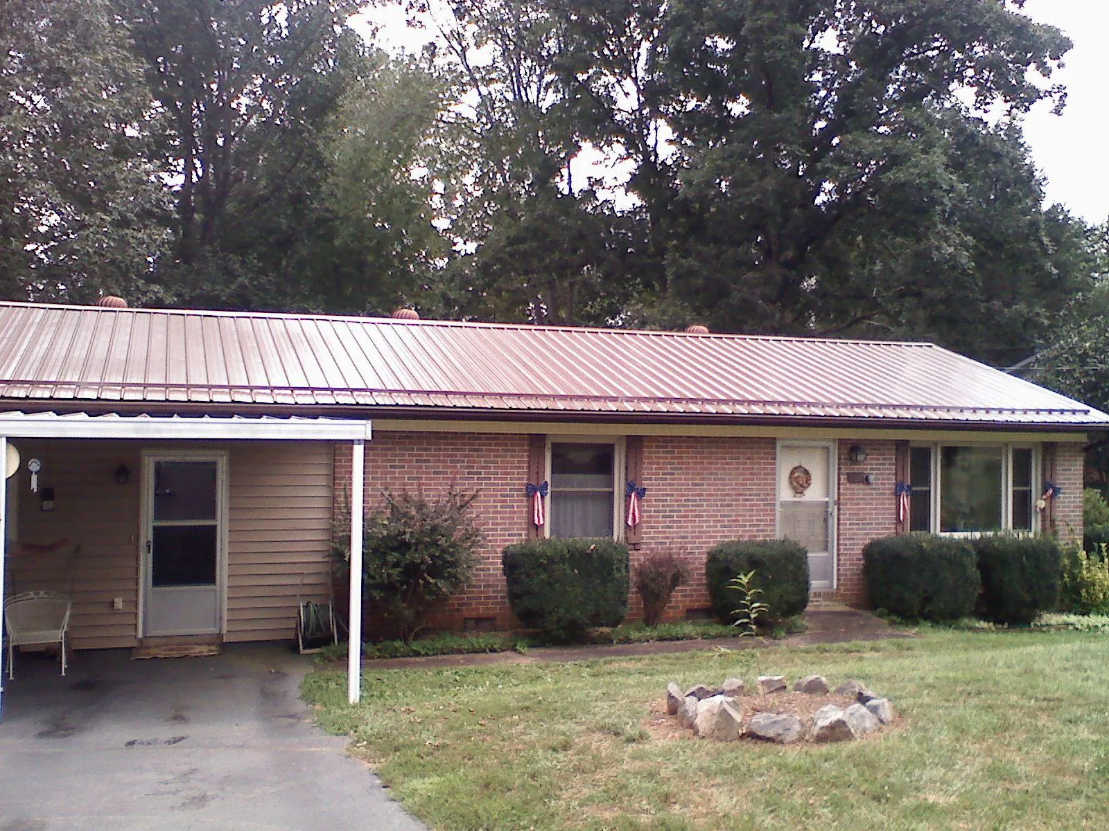 Bronze metal roof and carport on a brick ranch home — Roof Repair work by our crew in Martell