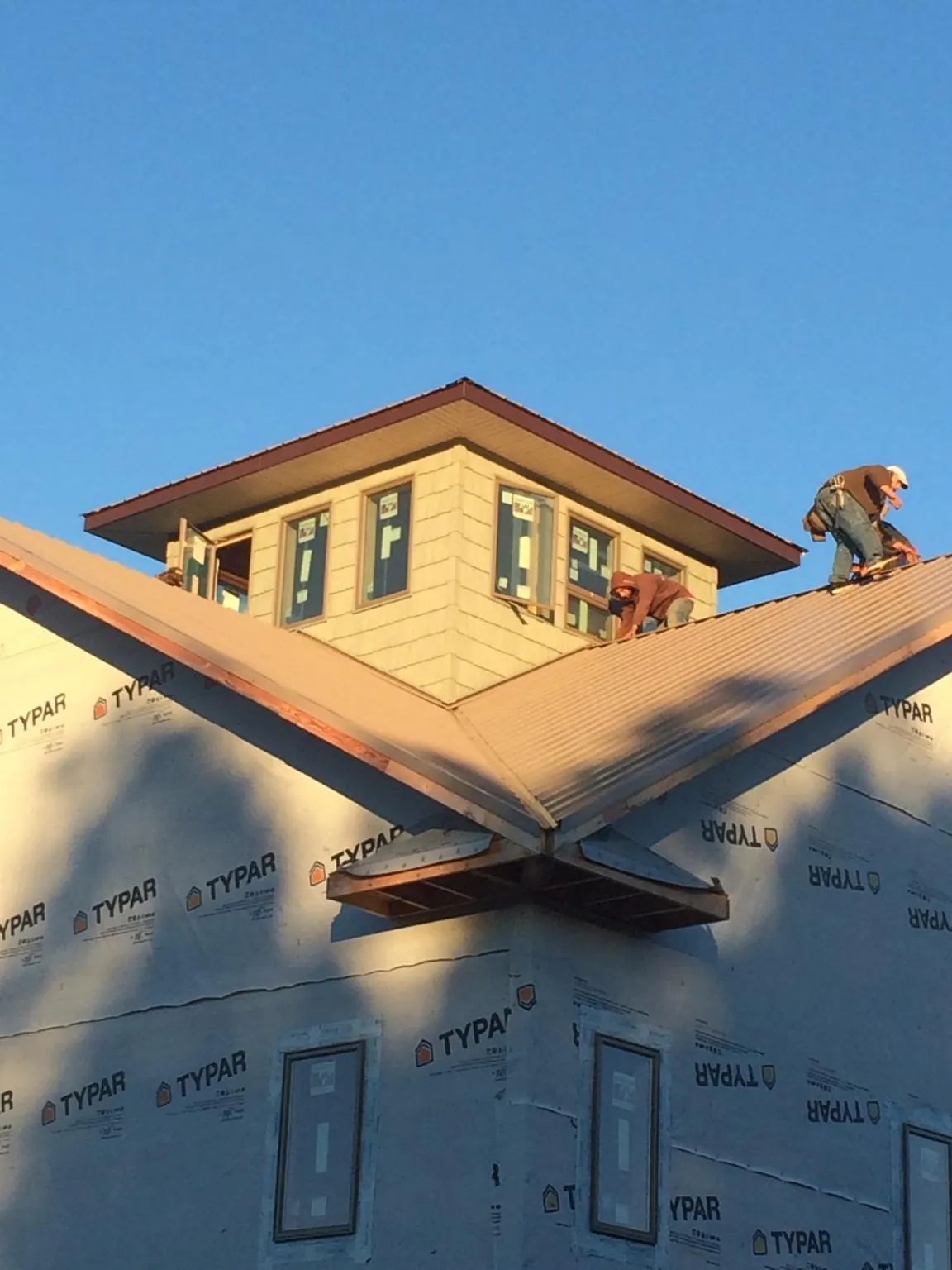 Roofers working around a rooftop cupola on a new metal roof at sunset — Roof Waterproofing in Martell by Roofing Brothers